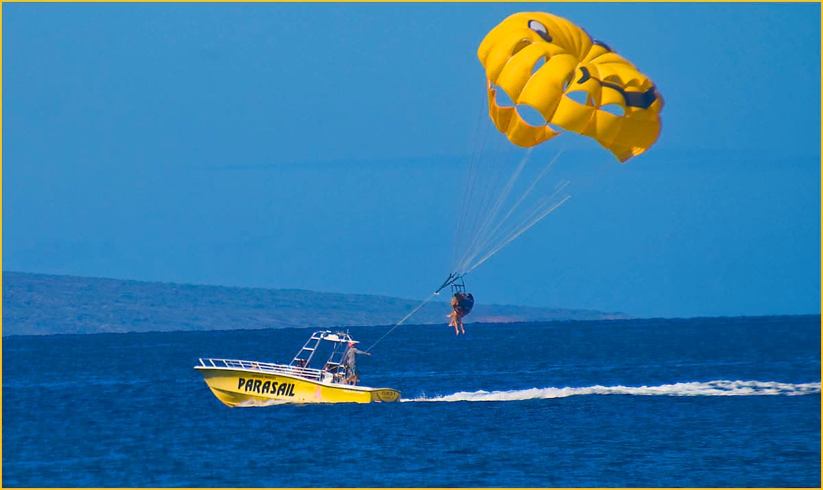 Yellow boat pulling two people parasailing on Maui