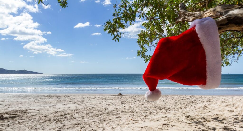 Santa hat on tropical Maui beach with turquoise ocean and palm trees during Christmas vacation